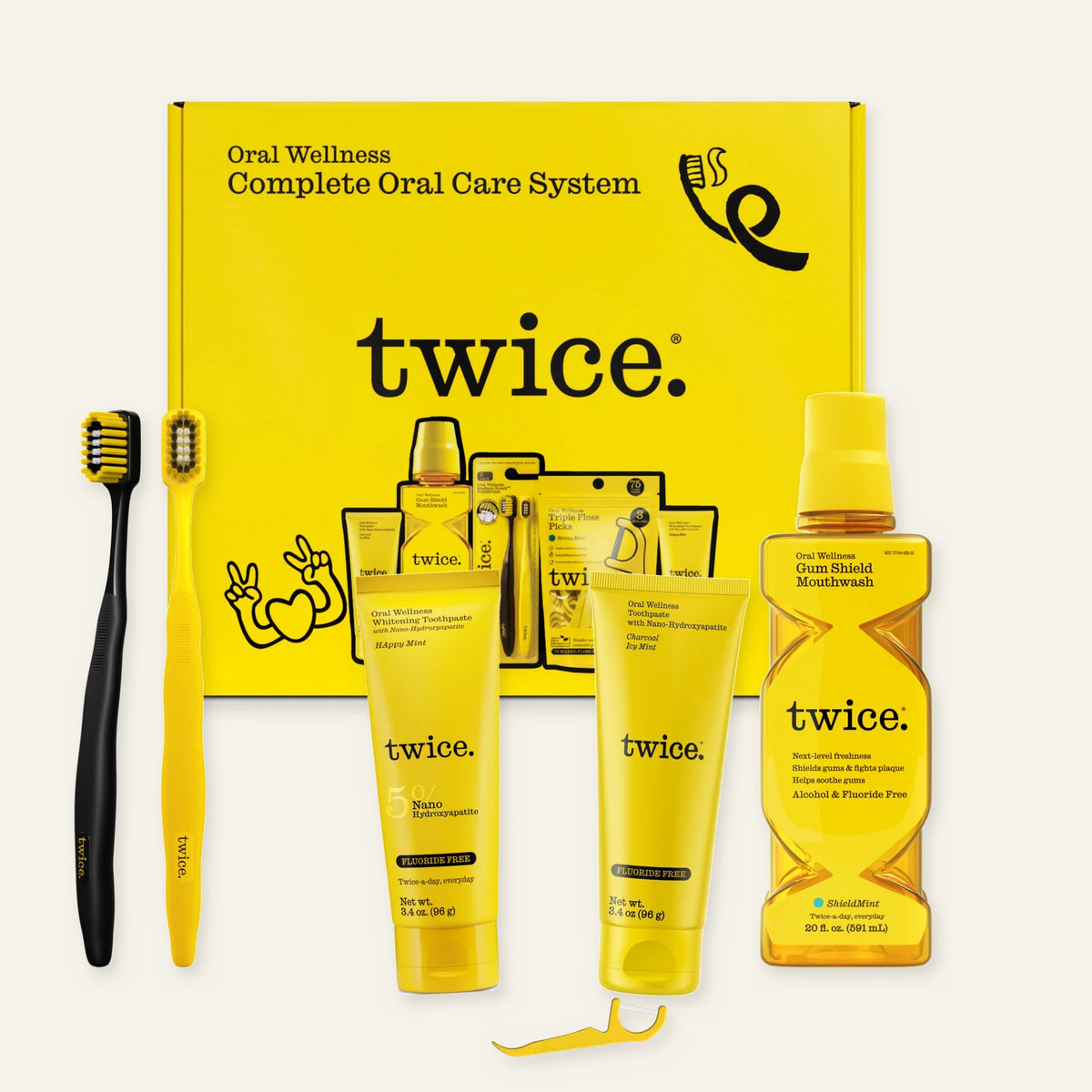 TWICE Complete Oral Care System box with Happy Mint and Charcoal Icy Mint toothpastes, Gum Shield Mouthwash, two Stadium Toothbrushes and a representative Triple Floss Pick. The set includes 75 picks.
