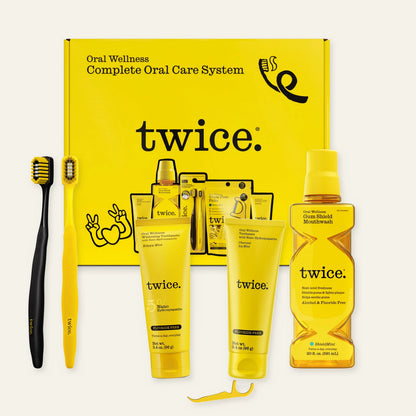 TWICE Complete Oral Care System box with Happy Mint and Charcoal Icy Mint toothpastes, Gum Shield Mouthwash, two Stadium Toothbrushes and a representative Triple Floss Pick. The set includes 75 picks.