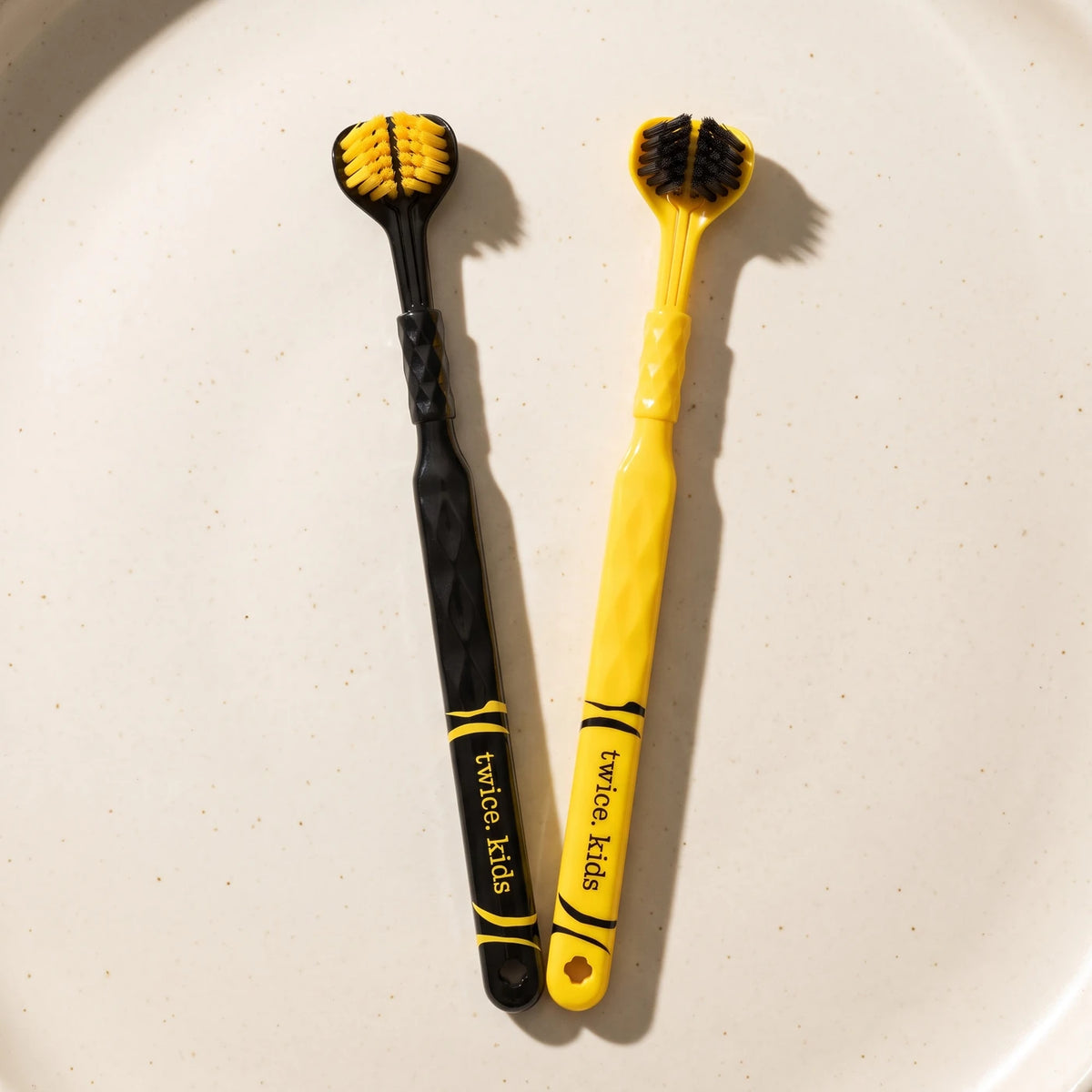 Two current Tiger-Tough Kids Triple Head toothbrushes with striped black and yellow handles