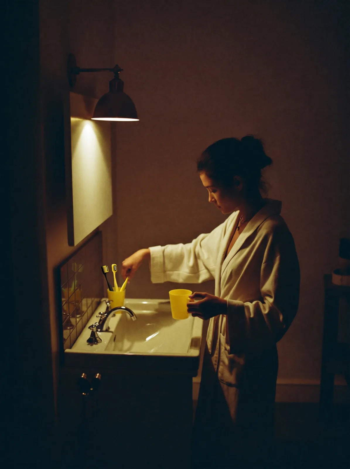A quiet evening at the bathroom sink, with warm light and yellow accessories.