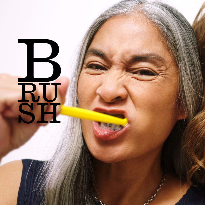 Two women brushing their teeth with toothbrushes, with 'BRUSH' text overlay.